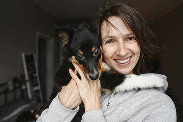 Smiling woman with dog at home - EYAF02925