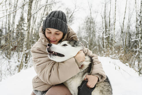 Frau umarmt Husky-Hund im Winter - EYAF02927