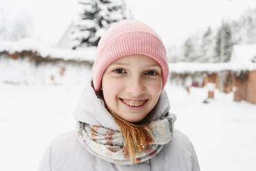 Lächelndes Mädchen mit Zahnspange und warmer Kleidung im Winter - EYAF02929