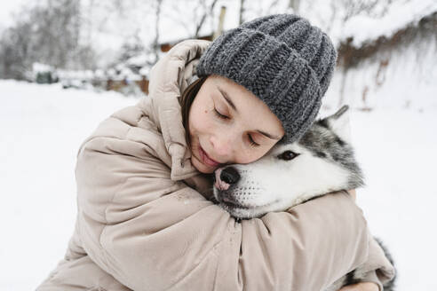 Frau umarmt Husky-Hund im Winter - EYAF02931