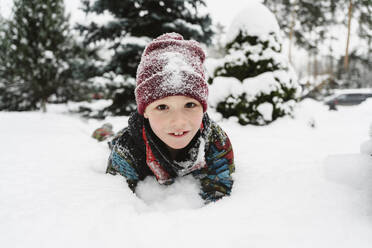 Verspielter Junge im Schnee liegend - EYAF02932