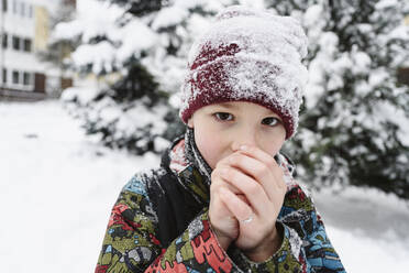 Junge bläst im Winter auf kalte Hände - EYAF02936