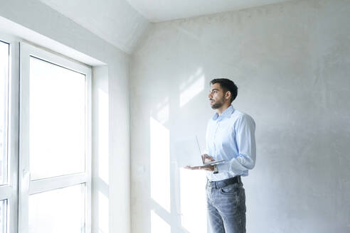 Nachdenklicher Architekt mit Laptop auf der Baustelle - AAZF01388