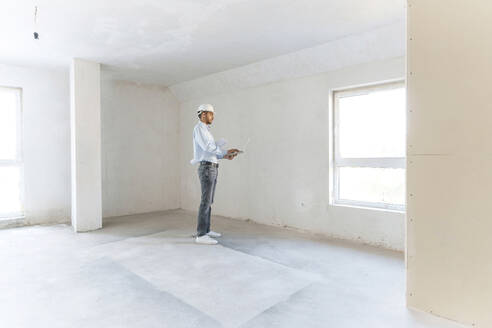 Architect working on laptop at construction site - AAZF01400