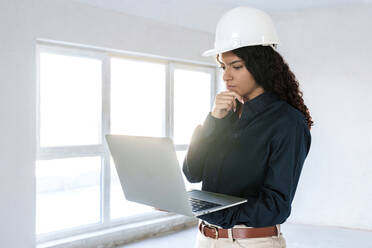 Architekt mit Schutzhelm und Laptop auf der Baustelle - AAZF01407