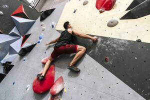 Athlete climbing on boulder wall in gym - PBTF00398