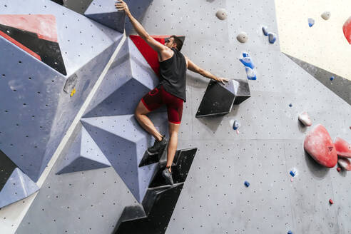 Sportler klettert an der Wand in der Boulderhalle - PBTF00399