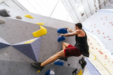 Sportler beim Bouldern an der künstlichen Kletterwand in der Sporthalle - PBTF00401