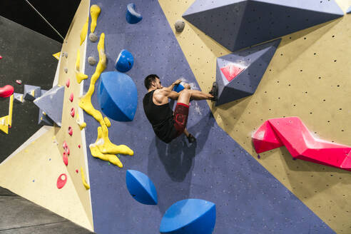 Sportler klettert an der Boulderwand in der Sporthalle - PBTF00402