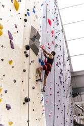 Sportler mit Sicherheitsgurt beim Klettern an einer Boulderwand - PBTF00406