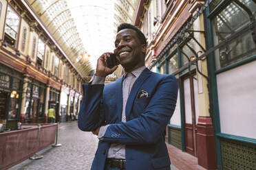 Happy businessman talking on smart phone at street - OIPF03794