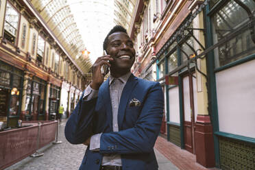 Smiling businessman talking on smart phone at street - OIPF03795