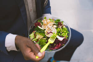 Businessman holding fork and having bowl of salad - OIPF03818