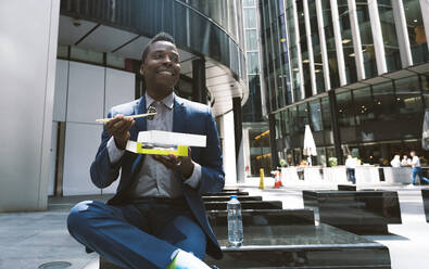 Smiling businessman having lunch at office park - OIPF03837