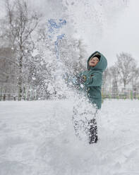 Verspielter Junge wirft im Park Schnee in die Luft - MBLF00247