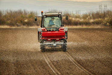 Landwirt im Traktor beim Sprühen von Dünger auf dem Feld - NOF00909