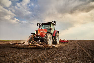 Landwirt pflügt Feld mit Traktor an einem bewölkten Tag - NOF00918