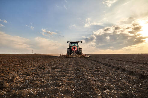 Landwirt im Traktor pflügt Feld an einem bewölkten Tag - NOF00919