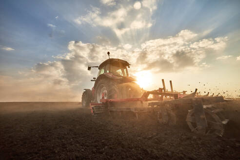 Traktor pflügt Feld bei Sonnenuntergang - NOF00920
