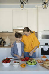 Glückliche Geschwister bei der Essenszubereitung in der Küche zu Hause - LESF00519