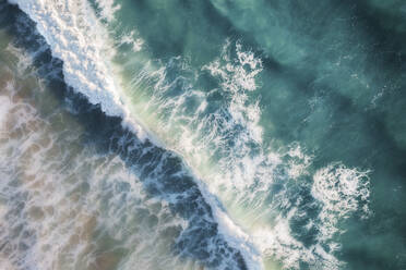 Große, sich bewegende Meereswellen mit kristallklarem, blauem Wasser und weißer Gischt, aufgenommen von oben, Port Noarlunga, South Australia, Australien. - AAEF25240