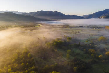 Luftaufnahme eines nebelverhangenen Tals im Frühnebel zwischen Bergen in Psaka, Epirus, Griechenland. - AAEF25469