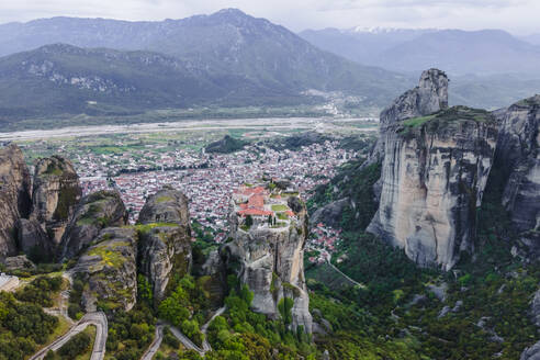 Luftaufnahme des orthodoxen Klosters der Heiligen Dreifaltigkeit mit der Stadt Kalabaka im Hintergrund bei Sonnenuntergang, Meteora, Kalabaka, Thessalien, Griechenland. - AAEF25487