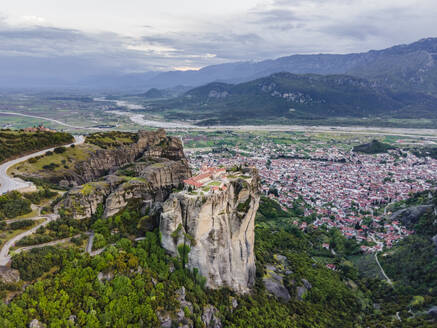 Luftaufnahme des orthodoxen Klosters der Heiligen Dreifaltigkeit mit der Stadt Kalabaka im Hintergrund bei Sonnenuntergang, Meteora, Kalabaka, Thessalien, Griechenland. - AAEF25488