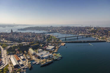 Aerial view of a boat sailing the Golden Horn waterway with Ataturk Bridge and Galata Bridge connecting the European Side of Istanbul downtown, Turkey. - AAEF25522