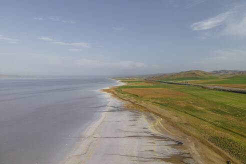 Aerial view of a road driving along the Tuz Golu (Lake Tuz), one of the largest hyper saline lake in the world, Central Anatolia Region, Turkey. - AAEF25532