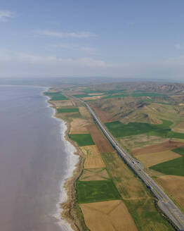 Aerial view of vehicles driving a scenic road along Lake Tuz (Tuz Golu), one of the largest hyper saline lake in the world, Central Anatolia Region, Ankara, Turkey. - AAEF25535