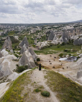 Luftaufnahme einer Frau mit Blick auf das Goreme-Tal und den Nationalpark mit Feenkamin-Felsformation und Canyons, Kappadokien, Nevsehir, Türkei. - AAEF25544