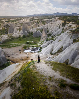 Luftaufnahme einer Frau mit Blick auf das Goreme-Tal und den Nationalpark mit Feenkamin-Felsformation und Canyons, Kappadokien, Nevsehir, Türkei. - AAEF25546