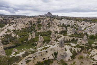 Aerial view of Goreme Valley and National Park with fairy chimney rock formation with Uchisar castle and town in background Cappadocia, Nevsehir, Turkey. - AAEF25554