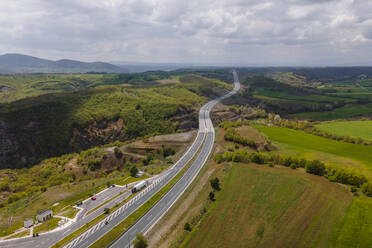 Luftaufnahme von Fahrzeugen auf der Autobahn inmitten der Berge in Taxiarchis, Westmakedonien, Griechenland. - AAEF25632