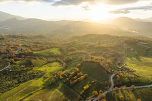 Luftaufnahme einer Berg- und Hügellandschaft mit Weinbergen und Häusern auf dem Land bei Sonnenuntergang in Herbstfarben, Irpinia, Avellino, Kampanien, Italien. - AAEF25756