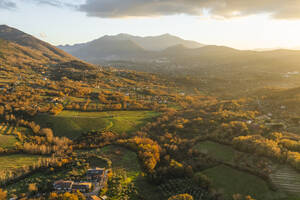 Luftaufnahme einer Berg- und Hügellandschaft mit Weinbergen und Häusern auf dem Land bei Sonnenuntergang in Herbstfarben, Irpinia, Avellino, Kampanien, Italien. - AAEF25771