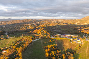 Luftaufnahme einer Berg- und Hügellandschaft mit Weinbergen und Häusern auf dem Land bei Sonnenuntergang in Herbstfarben, Irpinia, Avellino, Kampanien, Italien. - AAEF25774