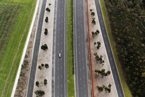 Aerial perspective of a single car driving on a contemporary highway, Australia. - AAEF25995