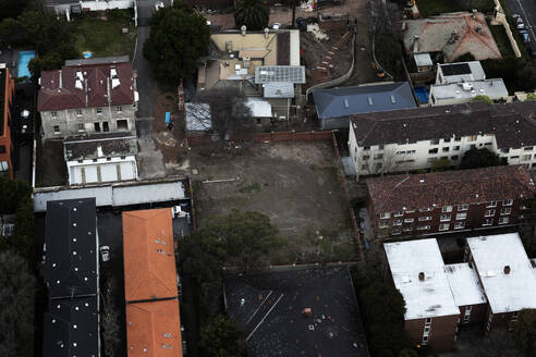 Luftaufnahme eines leeren Häuserblocks, umgeben von städtischen Wohnungen, die den Kontrast zwischen freiem Raum und städtischer Bebauung zeigen, Australien. - AAEF26003
