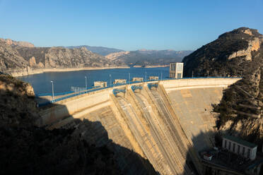 A vast dam with significantly reduced water levels in a mountainous area showcasing the potential effects of drought - ADSF52692