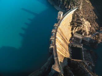 Top view dramatic aerial perspective of a dam casting long shadows across the water at sunrise or sunset - ADSF52696