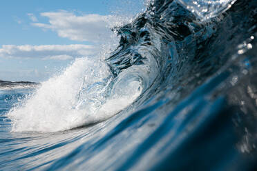 A close-up view of a sunlit wave cresting and curling with crystal-clear detail against a bright sky - ADSF52698