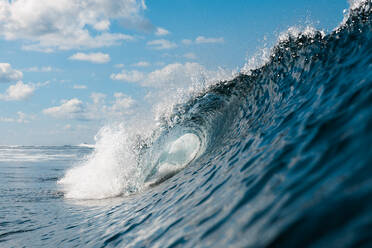 A dynamic close-up view of a cresting ocean wave, with a clear blue sky in the distance, showcasing the power and beauty of the sea - ADSF52699