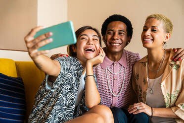 Group of friends bonding at home, LGBTQ and diversity concepts - Homosexual couple and fluid gender non binary young man with cross dressing clothing style having fun in the apartment, LGBT people concepts - DMDF09208