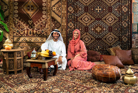 Junges Paar aus den Emiraten verbringt Zeit in einem traditionellen arabischen Café. Mann und Frau mit Kandura und Abaya aus Dubai unterhalten sich. - DMDF09286