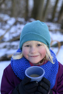 Lächelndes Mädchen in warmer Kleidung und mit Tasse im Winter - GISF01020