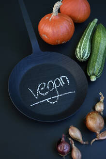 Studio shot of vegetables and black frying pan with word vegan written in chalk - GISF01021