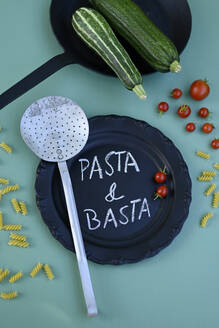 Studio shot of vegetables, pasta, sieve, frying pan and black plate with short phrase written in chalk - GISF01022