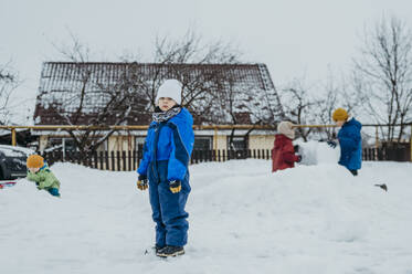 Kinder tragen warme Kleidung und spielen im Schnee - ANAF02661